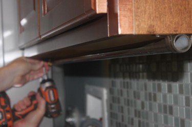 Cheap DIY Clothes Rack. Hang laundry with an easy to make undercabinet retractable clothes rod.