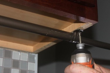 Cheap DIY Clothes Rack. Hang laundry with an easy to make undercabinet retractable clothes rod.